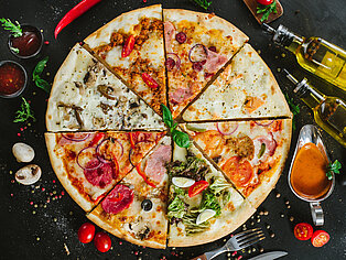 Verschiedene Pizzastücke, aus denen eine ganze Pizza besteht